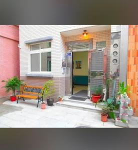un banc assis devant une maison avec des plantes dans l'établissement 拼圖休閒民宿, à Hsia-pu-hsia