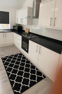 une cuisine avec des armoires blanches et un tapis à motifs noirs et blancs dans l'établissement Modern 3 Bed with 3 Baths and Parking, Near Centre, à Bredbury