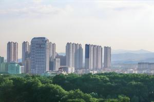 南昌市にあるXana Lite·Nanchang Changbei Jiangxi University of Finance and Economicsの高い建物と木々のある街のスカイライン