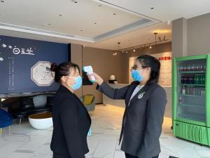 zwei Frauen mit Gesichtsmasken in einem Laden in der Unterkunft Magnotel Business Harbin Railway Station Qiulin Museum Metro Station in Harbin