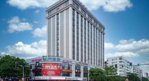 ein hohes weißes Gebäude mit einem Bus davor in der Unterkunft Longuu Hotel Zhaoqing in Zhaoqing