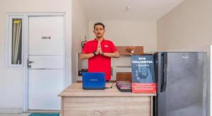 un homme debout dans une cuisine avec les bras croisés dans l'établissement OYO Living 1877 Side Corner, à Kanggraksan 68 autres photos