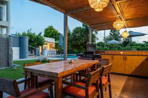 a patio with a wooden table and a stove at INFINITY PREMIUM Villas in Kos Town
