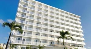 TakaraにあるHotel Gran View Okinawaのヤシの木が前に立つ大きな白い建物