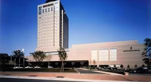 a large white building with a tall building at Grand Hotel New Oji in Ōjimachi