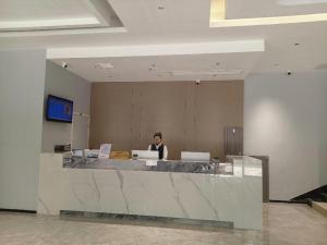 Pingxiangにある7 Days Inn Pingxiang Railway Stationの職場の窓口に座る男