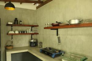 a kitchen with a stove and shelves on the wall at The Drop In Surfhouse Madiha in Madihe East
