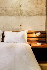 a bed with white sheets and a lamp on a table at Hidden Gem Llandudno Studio in Llandudno