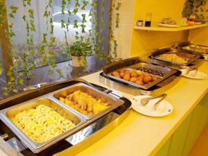 a kitchen with several trays of food on a counter at GreenTree Inn Hefei Huangshan Road Business Hotel in Hefei