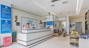 Eine Lobby eines Krankenhauses mit einer Frau, die an einem Tresen steht. in der Unterkunft Xana Lite Beijing Shunyi Metro Station in Shunyi