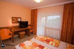 a hotel room with a bed and a desk and a window at Penzion Tara in Veľký Meder