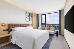 a bedroom with a large white bed and a window at Four Points by Sheraton Haikou International Airport in Haikou