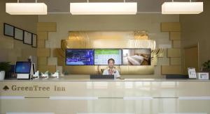 a man sitting at a counter in an office at GreenTree Inn Suqian Suyu District Red Star Macalline in Zhuoxu