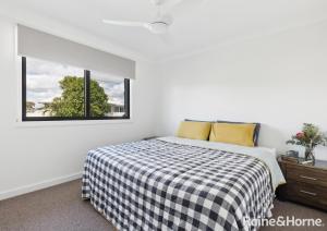 a bedroom with a bed with a checkered blanket and two windows at Mariners Rest in Yamba +4 photos