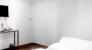 Dieses weiße Zimmer verfügt über ein Bett und einen TV. in der Unterkunft Capital O 75412 V Resort in Ban Wang Ton