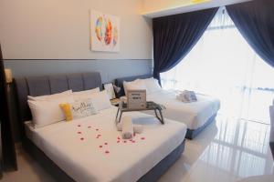 2 Betten in einem Hotelzimmer mit Blumen darauf in der Unterkunft Grand Medini Residence By The one - Cozy Studio 5pax in Nusajaya + 38 Fotos