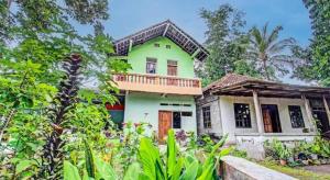 a green and white house with a balcony at SPOT ON 93592 Pondok Backpackers Ardafa Jogja in Manisrenggo