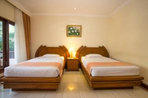 a bedroom with two beds and a lamp in it at Parigata Resorts and Spa in Sanur
