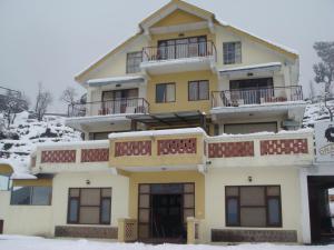 un edificio amarillo con balcones y nieve en el suelo en Dragon I Resorts, en McLeod Ganj