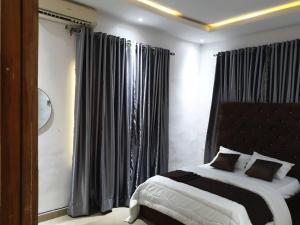 a bedroom with a large bed with black curtains at QW5 APARTMENTS and SUITE in Lekki +2 photos