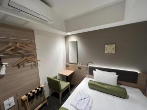 Un dormitorio con una cama y una silla verde. en KEIKYU EX INN Hamamatsucho Daimon-Station (Tokyo), en Tokio