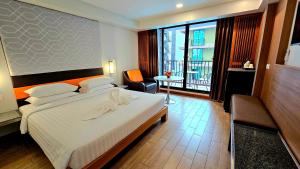 バンコクにあるダイナスティ グランデ ホテルの大きな白いベッドとバルコニーのある寝室