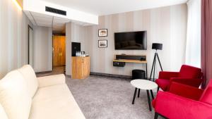 a living room with red chairs and a flat screen tv at Czarna Perła Apartamenty z bezpłatnym basenem Czarna Góra Resort in Sienna