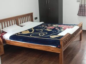 een bed met een houten frame met een blauwe deken bij Cherry Blossom in Kotagiri