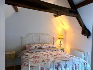 ein Schlafzimmer mit einem weißen Bett mit rosa Blumen in der Unterkunft Charming Grade 2 Cottage w/ Garden in Warminster in Warminster