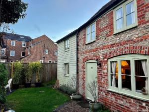 ein Backsteinhaus mit einer grünen Tür in einem Hof in der Unterkunft Charming Grade 2 Cottage w/ Garden in Warminster in Warminster