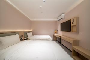 a hotel room with two beds and a flat screen tv at Yinuo Premium Hotel in Guangzhou