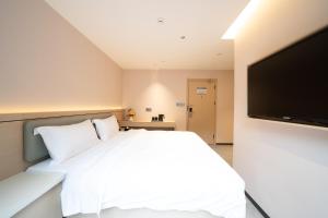 a bedroom with a white bed and a flat screen tv at Yinuo Premium Hotel in Guangzhou