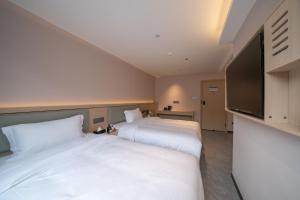 two beds in a hotel room with a flat screen tv at Yinuo Premium Hotel in Guangzhou