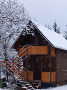 Una cabaña de troncos con techo cubierto de nieve y escaleras. en Cabana Cavnic Maramures, en Cavnic