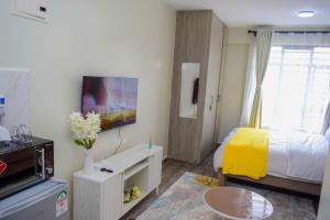 a small room with a bed and a tv at Stayride Homes in Ruaka