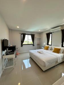 a bedroom with a large white bed and a desk at DAAD FAH home and cafe in Phetchaburi