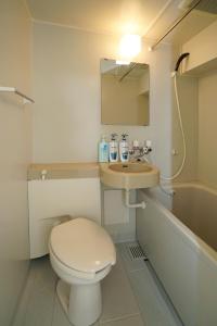 La salle de bains est pourvue de toilettes, d'un lavabo et d'une baignoire. dans l'établissement Tobi Hostel and Apartments, à Shima