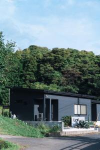 una casa blanca y negra con una colina detrás en Laf Denen 千葉県富津市のvacation rental, en Futtsu