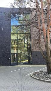 Ziogu Apartments في بالانغا: مبنى زجاجي كبير امامه شجرة