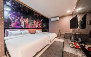 a hotel room with a large white bed and a tv at The Oreun Echae Hotel in Jeju