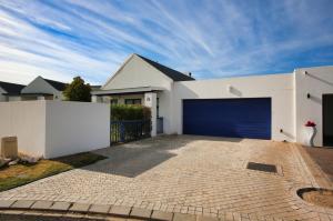 ein weißes Haus mit einer blauen Garagentür in der Unterkunft Noa Haven, Langebaan, 4 Sleeper in Langebaan