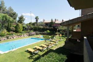 a swimming pool with lounge chairs next to a house at SeaHomes Vacations - Cala Banys Seafront Apt & PKG in Lloret de Mar