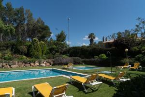 a backyard with a pool with chairs and a swimming pool at SeaHomes Vacations - Cala Banys Seafront Apt & PKG in Lloret de Mar