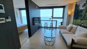 a living room with a couch and a table at Charman Ocean View Sunrise 10 seconds to the beach in Kwangan-dong