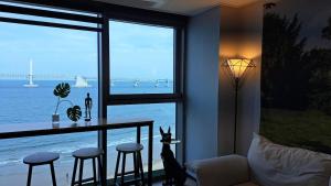 a living room with a large window with a view of the ocean at Charman Ocean View Sunrise 10 seconds to the beach in Kwangan-dong