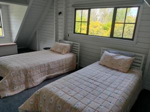 a bedroom with two beds and a window at Hawkings Lodge in Kerikeri