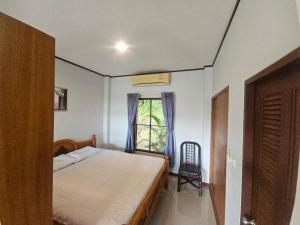 a bedroom with a bed and a window with a chair at Seaview Studio Jungle in Lamai