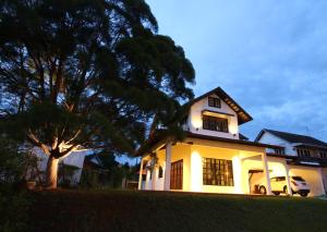 a white house with a tree in front of it at The Pines Cottage in Melaka