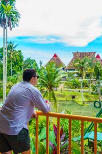 a man standing on a balcony looking at a resort at Hotel Deli River and Restaurant Omlandia in Medan