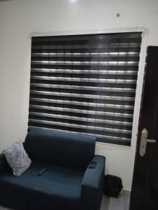 a blue couch in a living room with a window at Guest Apartments in New Weija